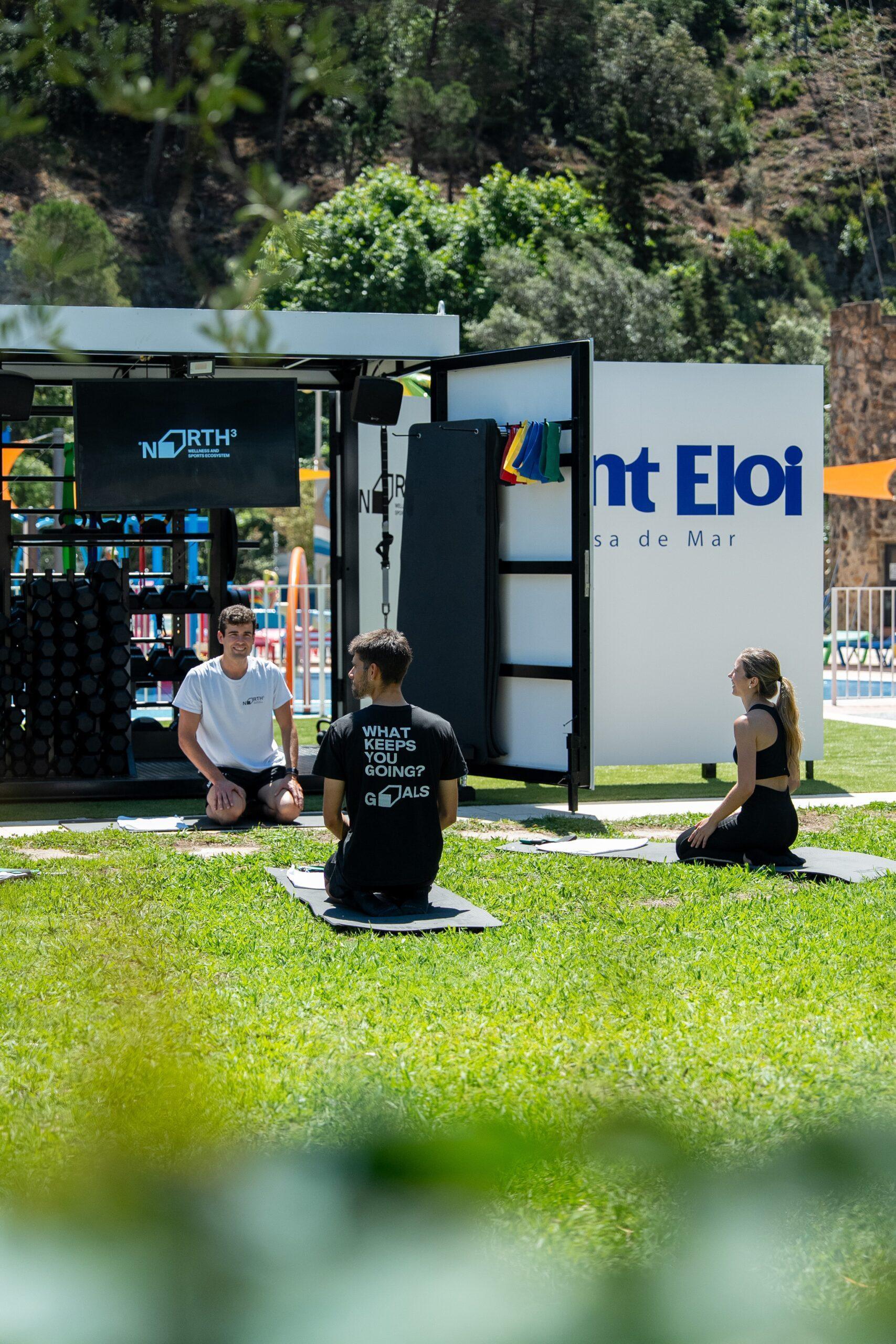 Tres persones entrenant a l'aire lliure amb el dispositiu WellCube davant de l'hotel Sant Eloi a Tossa de Mar
