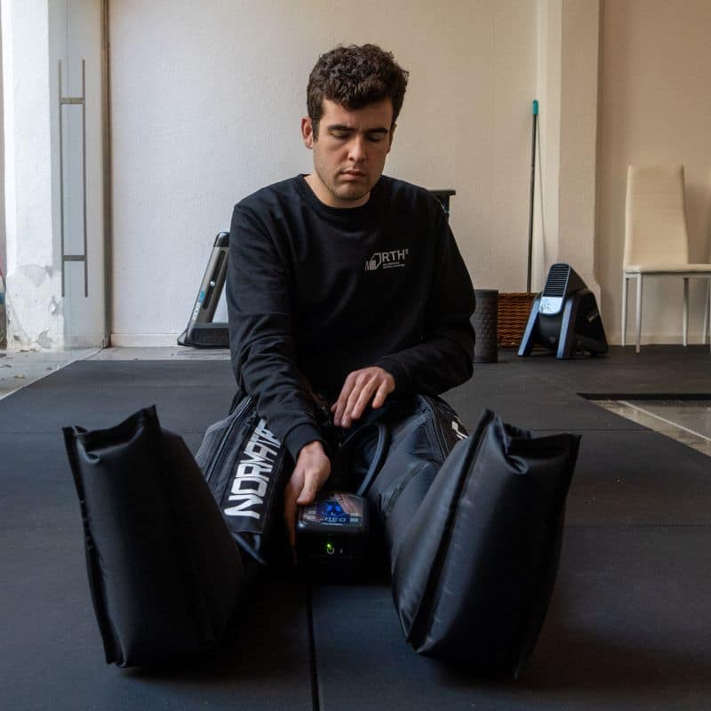 Usuari assegut al North3 Studio fent una sessió de recuperació amb botes de pressoteràpia Normatec